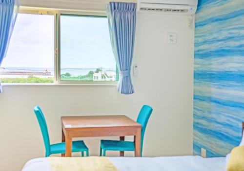 ヴィラアマルフィ パームスプリングス宮古島リゾート في جزيرة مياكو: طاولة وكراسي في غرفة مع نافذة