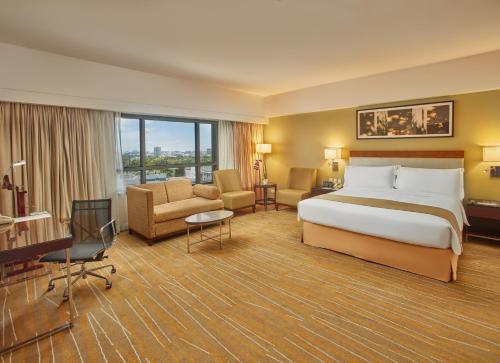 Holiday Inn & Suites Makati, an IHG Hotel في مانيلا: فندق كبير غرفه بسرير ومكتب