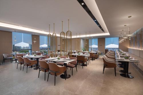 a dining room with tables and chairs and windows at Somerset Taihu New City CBD Wuxi in Wuxi