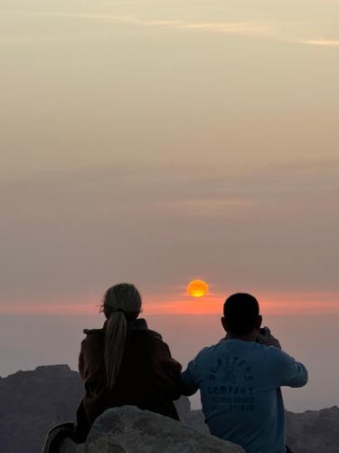 a couple sitting on a rock watching the sunset at Petra Desert Dream Hotel in Wadi Musa