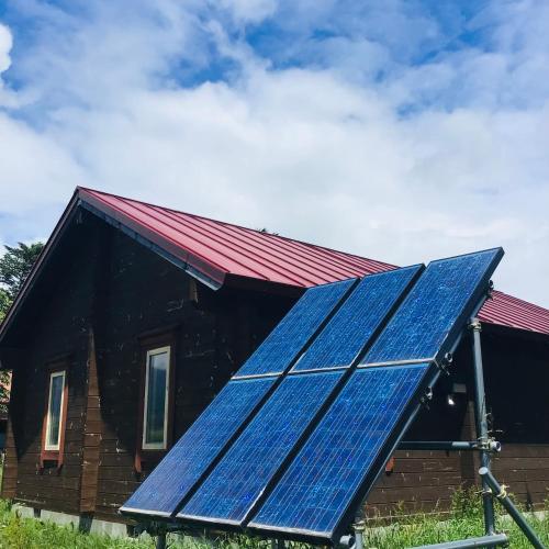 a house with a solar panel on the roof at Eco-friendly Log Cottage - be with nature in Furano