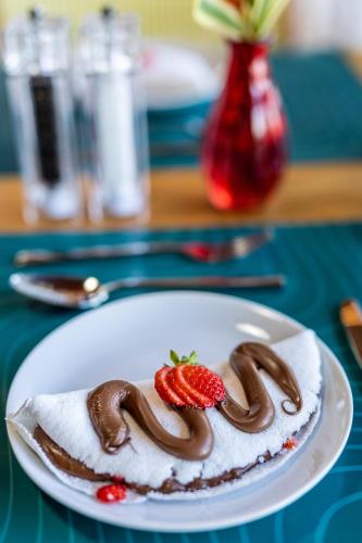 a white plate with a dessert with chocolate and strawberries at Duke Beach Hotel Maresias in Maresias