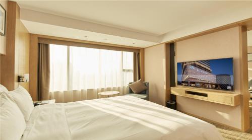 a hotel room with a bed and a tv at Zenith Hotel-Near Train Station & The Mixc in Xiamen