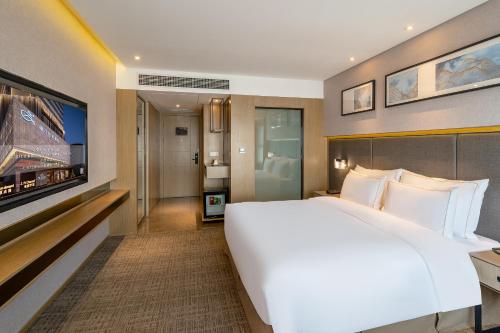 a bedroom with a large white bed and a television at Zenith Hotel-Near Train Station & The Mixc in Xiamen