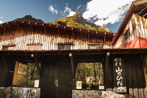 a wooden building with a mountain in the background at Yamano Hidaya in Matsumoto