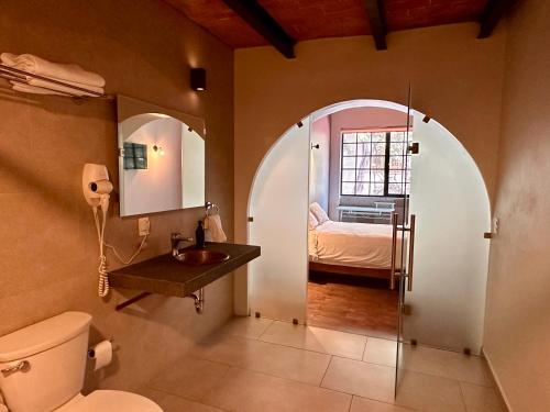a bathroom with a toilet and a sink and a bedroom at Casa Raffaello in Mexico City