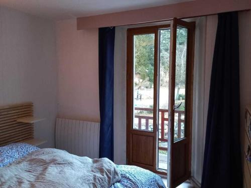 une chambre avec un lit et une porte coulissante en verre dans l'établissement Appartement Rénové 5 Pers avec WIFI et Animaux Acceptés - FR-1-512-273, à Brides-les-Bains