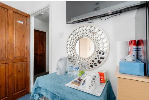 ein Badezimmer mit einem Tisch und einem Spiegel an der Wand in der Unterkunft North Avenue, Guest House, Heathrow Airport-Free Parking in Hayes
