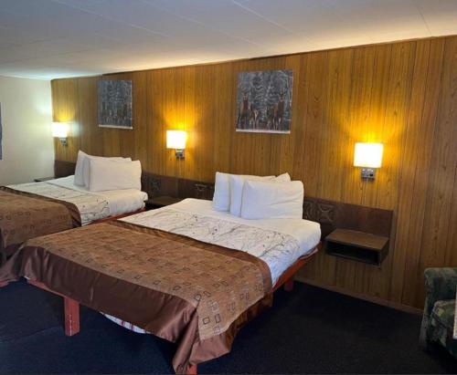 two beds in a hotel room with wooden walls at Robbie's Motel in Cache Creek