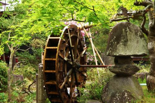 a wooden wheel in a garden next to a tree at Hohoemino Kuyufu Tsuruya in Tendo