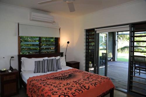 a bedroom with a bed and a sliding glass door at Tropika - Absolute Beachfront in Mission Beach