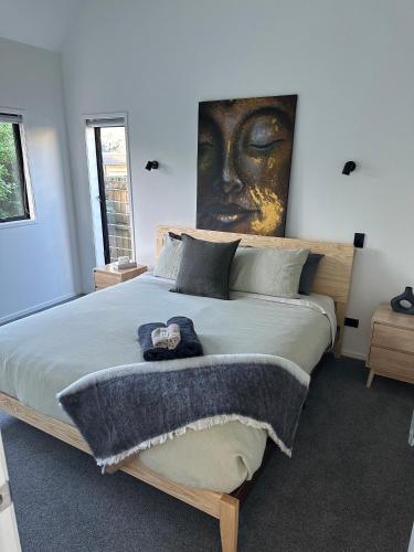 a bedroom with a large bed with a painting on the wall at Modern Two bedroom Oasis in Whangamata