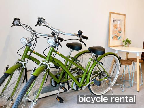 two green bikes parked next to a wall at THY GUEST HOUSE in Ise