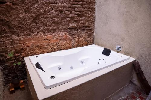 Real Santuario في غواذالاخارا: حوض استحمام أبيض يجلس بجوار جدار من الطوب