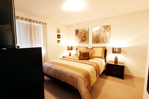 a bedroom with a bed and two paintings on the wall at Apt 8 'Aquilla' @ Bay View Centro, Dunsborough in Dunsborough