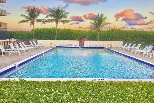 a large swimming pool with chairs and palm trees at Ocean Breeze Condo in Jensen Beach
