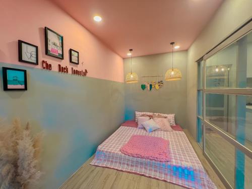 a small bedroom with a bed with a pink wall at Chon's Dock Homestay & Apartment For Lease in Phan Thiet
