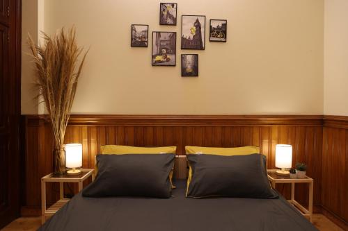 a bedroom with a bed with two lamps and pictures on the wall at Homestay cạnh Lăng Bác in Hanoi