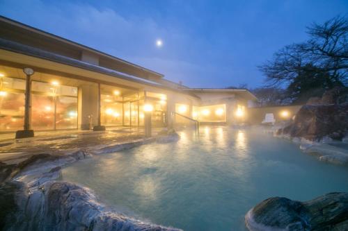 a swimming pool in front of a building at night at Kintarou Onsen in Uozu