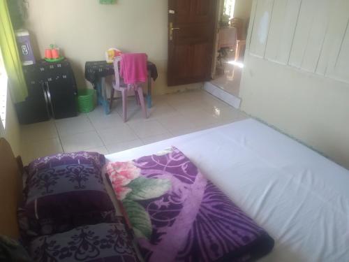 a bed in a room with a table and a chair at Karleta Homestay in Ruteng
