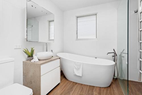 a white bathroom with a large tub and a sink at Collaroy Beachfront Escape - New Listing in Collaroy