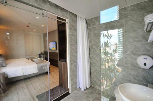 a bathroom with a bed and a shower and a sink at Ivy Hotel Nha Trang in Nha Trang