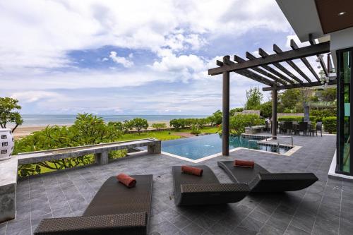 un patio al aire libre con piscina y pérgola en Beach Front 4 Bedroom Pool Villa VR, en Hua Hin