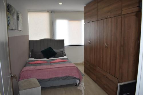 a bedroom with a bed and a large wooden cabinet at Tranquilo y Acogedor Apto en Fusagasugá. in Fusagasuga