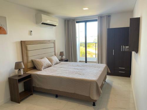 a bedroom with a bed and a large window at Bello monoambiente a metros del aeropuerto in Colonia Mariano Roque Alonso
