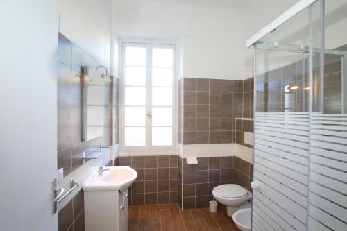 bagno con lavandino, servizi igienici e finestra. di 53 Solaro Apartments a Sanremo