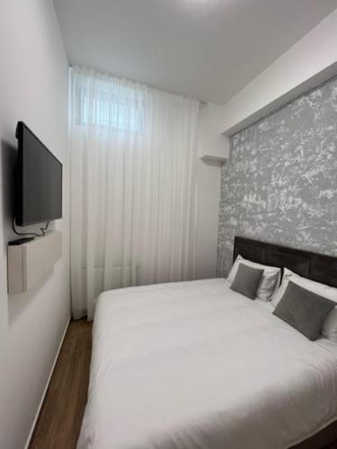 Un dormitorio con una cama blanca y un televisor de pantalla plana. en Centar NS 5, en Novi Sad