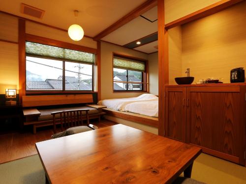 a bedroom with a wooden table and a bed and window at Ichidaya in Toyooka