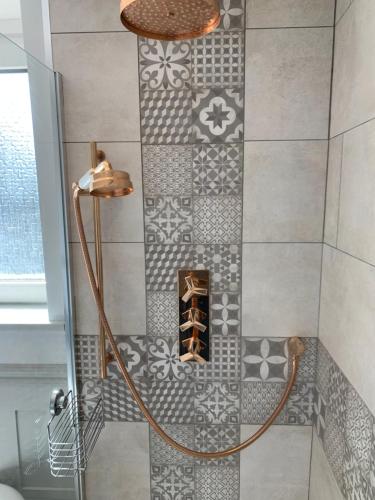 a shower with a tiled wall with a shelf at Honeycott in Crickhowell