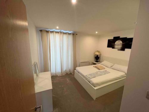 a white bedroom with a bed and a window at Avalon apartment city center of brighton & hove in Brighton & Hove
