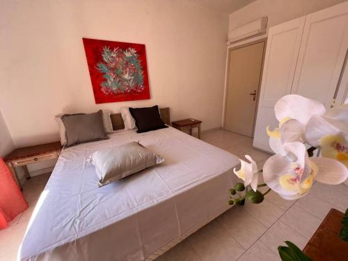1 cama blanca grande en un dormitorio con una pintura en Casa Viola, San Vito a 25 minuti da Costa Rey e Villasimius, en San Vito