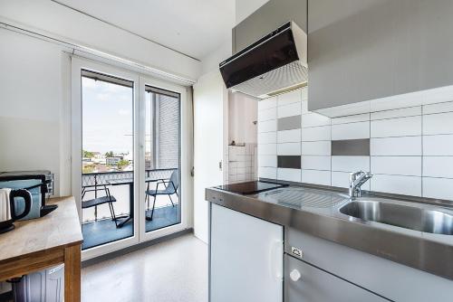eine Küche mit einer Spüle und Blick auf einen Balkon in der Unterkunft Cooldis 6 !Gratis Parken, Free Parking! in Kreuzlingen