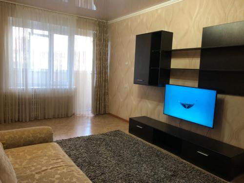 een woonkamer met een tv en een bed bij Квартира в Актау in Aqtau