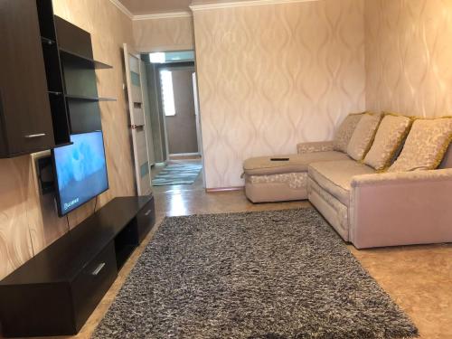 een woonkamer met een bank en een flatscreen-tv bij Квартира в Актау in Aqtau