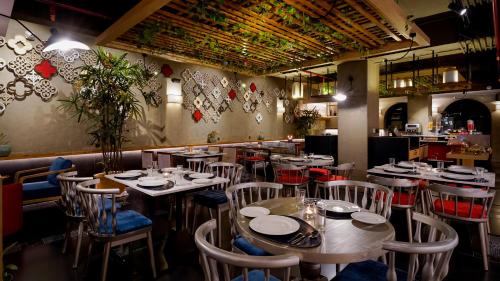 a restaurant with tables and chairs in a room at Aiden by Best Western Hennur Bengaluru in Bengaluru