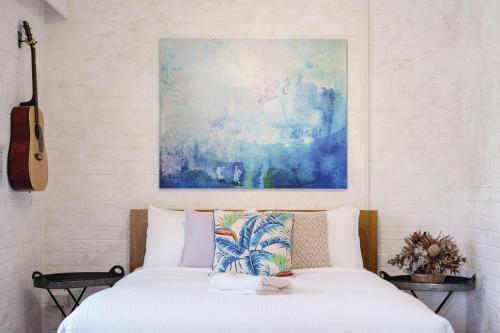 Un dormitorio con una cama con una guitarra y una pintura en Fingal Pines Getaway, Apartment, en Fingal Bay