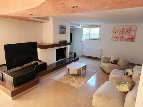 ein Wohnzimmer mit einem Flachbild-TV und einem Sofa in der Unterkunft Oasi Sul Golfo in Su Forti