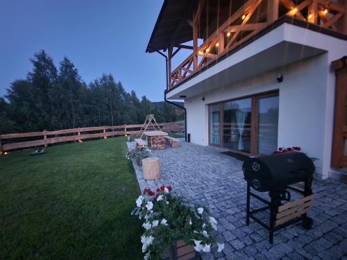 a backyard of a house with a grill and flowers at Dusznickie Apartamenty z widokiem in Duszniki Zdrój