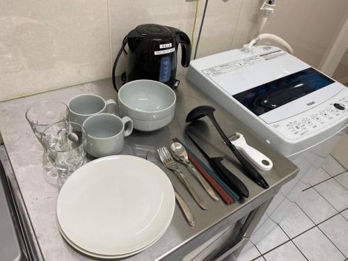 a kitchen counter with a stove and a plate and cups at ホテルトーマス牧志 in Naha