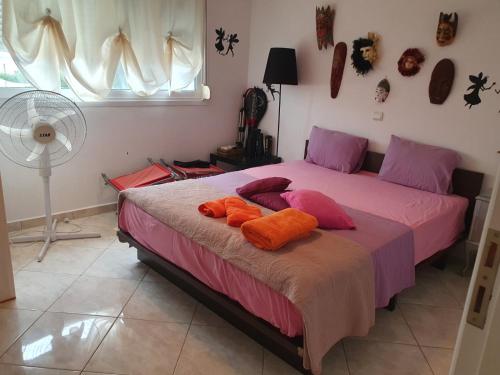 a bedroom with a bed with orange pillows and a fan at Evi in Xylokastro