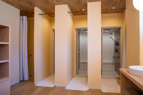 a bathroom with a walk in shower and a sink at Glamping&Port結 in Shimada