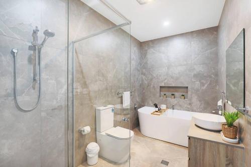 a bathroom with a shower and a toilet and a sink at Illalangi-Modern Escape & Views in Mudgee
