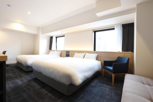 a hotel room with two beds and a chair at Henn na Hotel Premier Nagoya Fushimiekimae in Nagoya