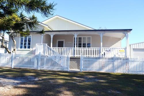 a white fence in front of a white house at Christina Cottage - Bring your own linen in South West Rocks