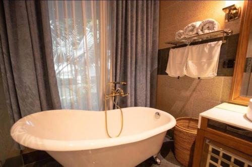 baño con bañera blanca y ventana en Riverside French Villa, en Thuan An
