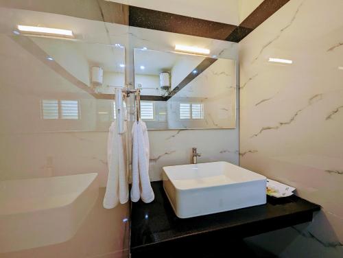 y baño con lavabo blanco y espejo. en TPC Camphor en Tiruchchirāppalli